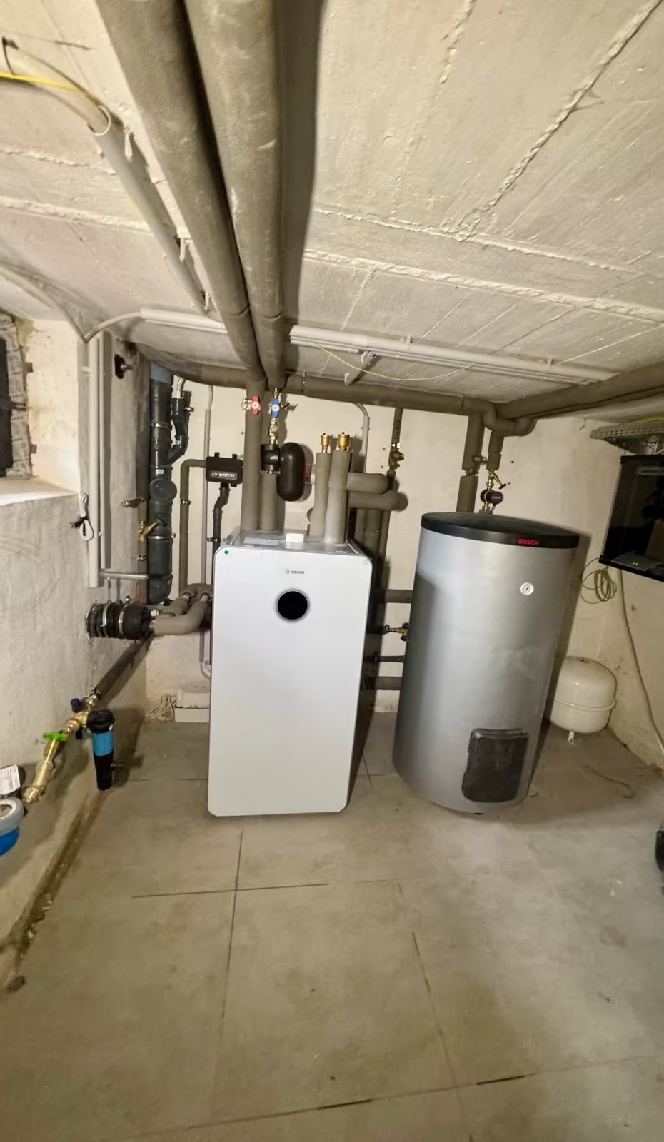 Zentrale Heizungsanlage mit Warmwasserspeicher in einem Kellerraum
